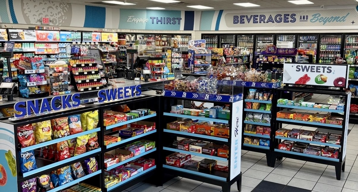 C-store front-end fixture system with branded Snacks and Sweets sections under Engage Thirst and Beverages and Beyond ceiling banners